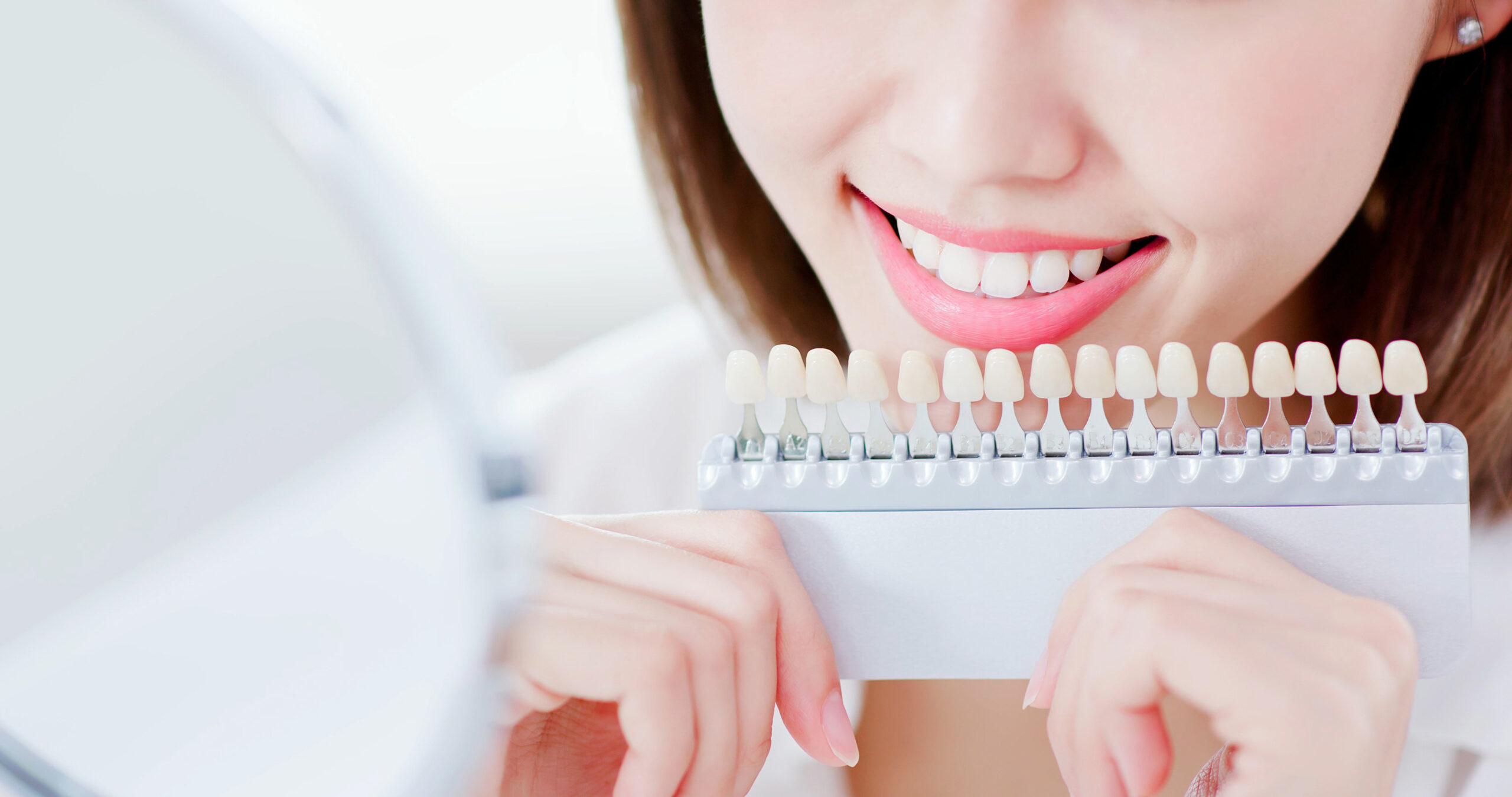 close up of beauty woman smile to you with health teeth and color samples tool for bleaching treatment