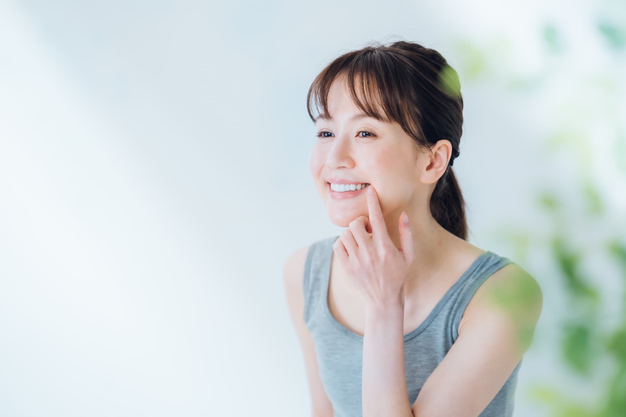 自費ブリッジできれいになった歯を指さし嬉しそうな女性