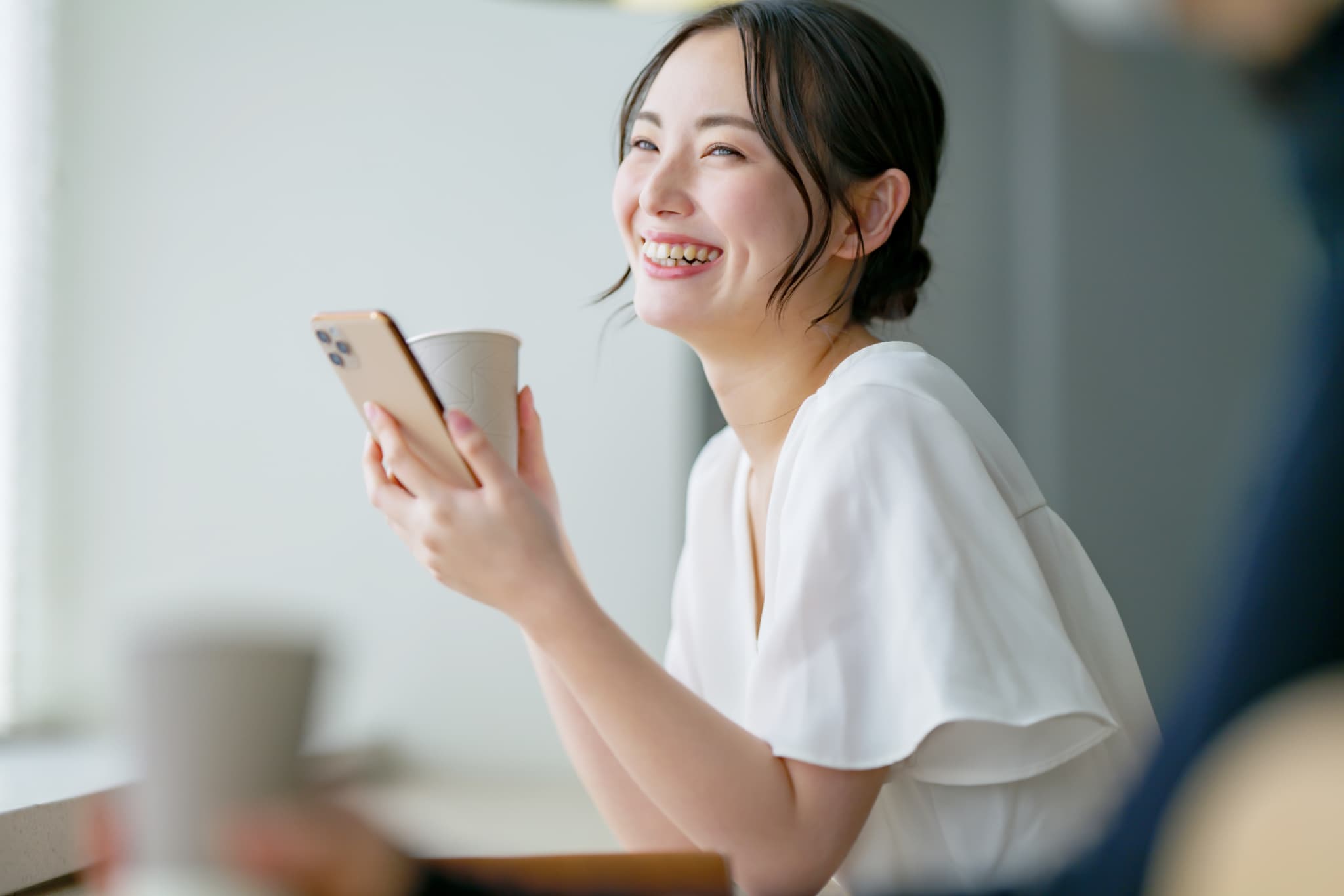 カフェでスマホを見る笑顔の女性