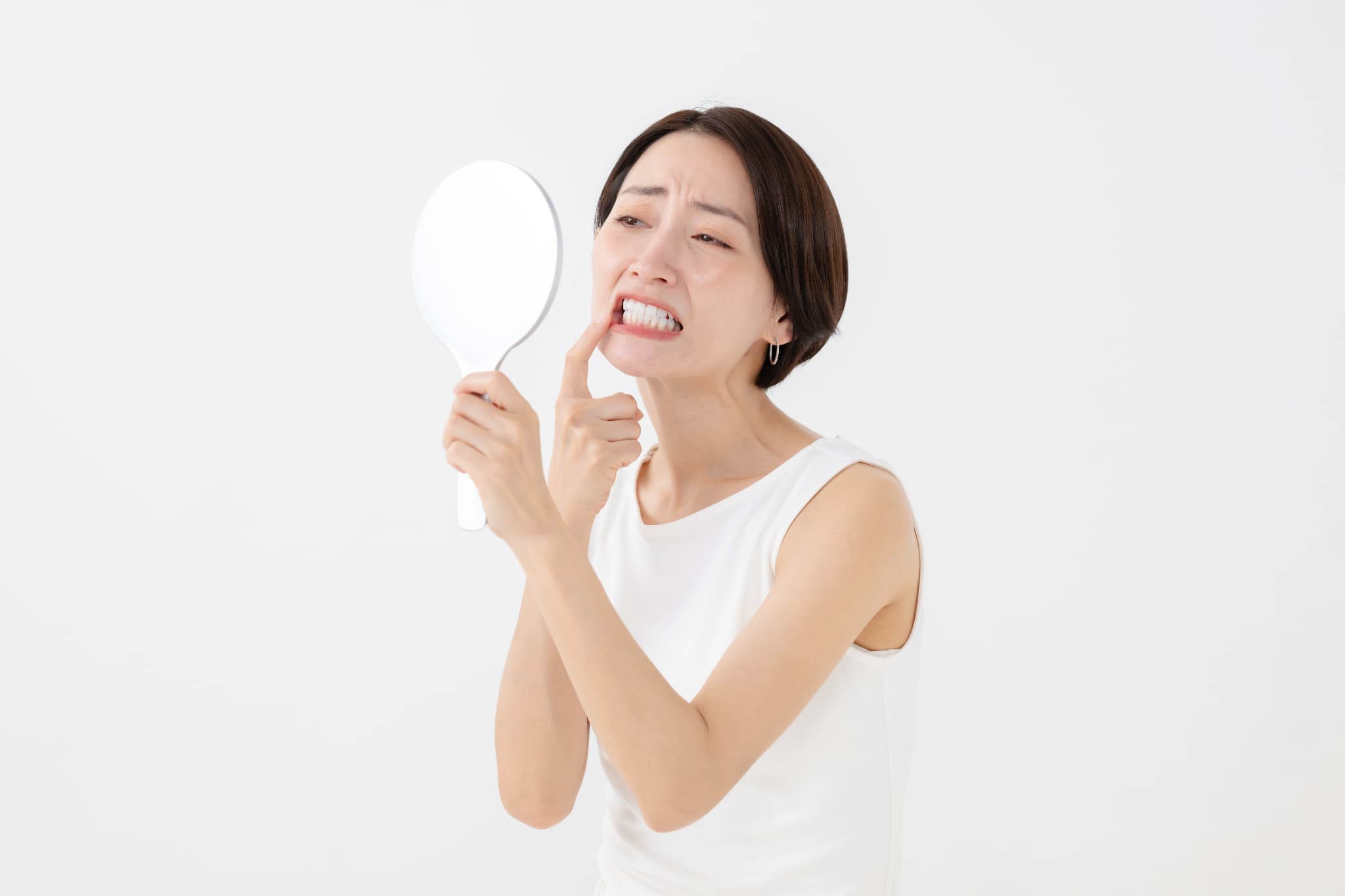 歯と歯の間が虫歯になっていないか鏡で確認する女性