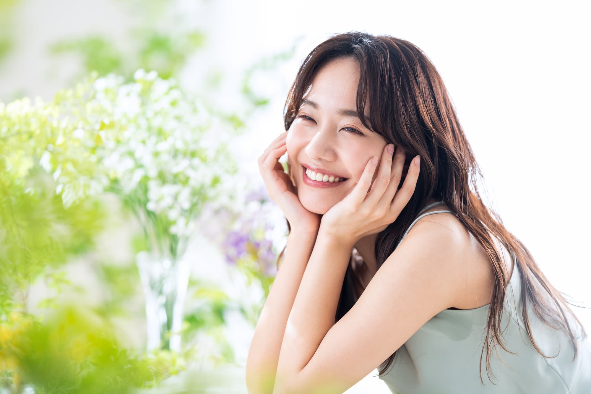 グリーンを背景に頬杖をつき微笑む女性