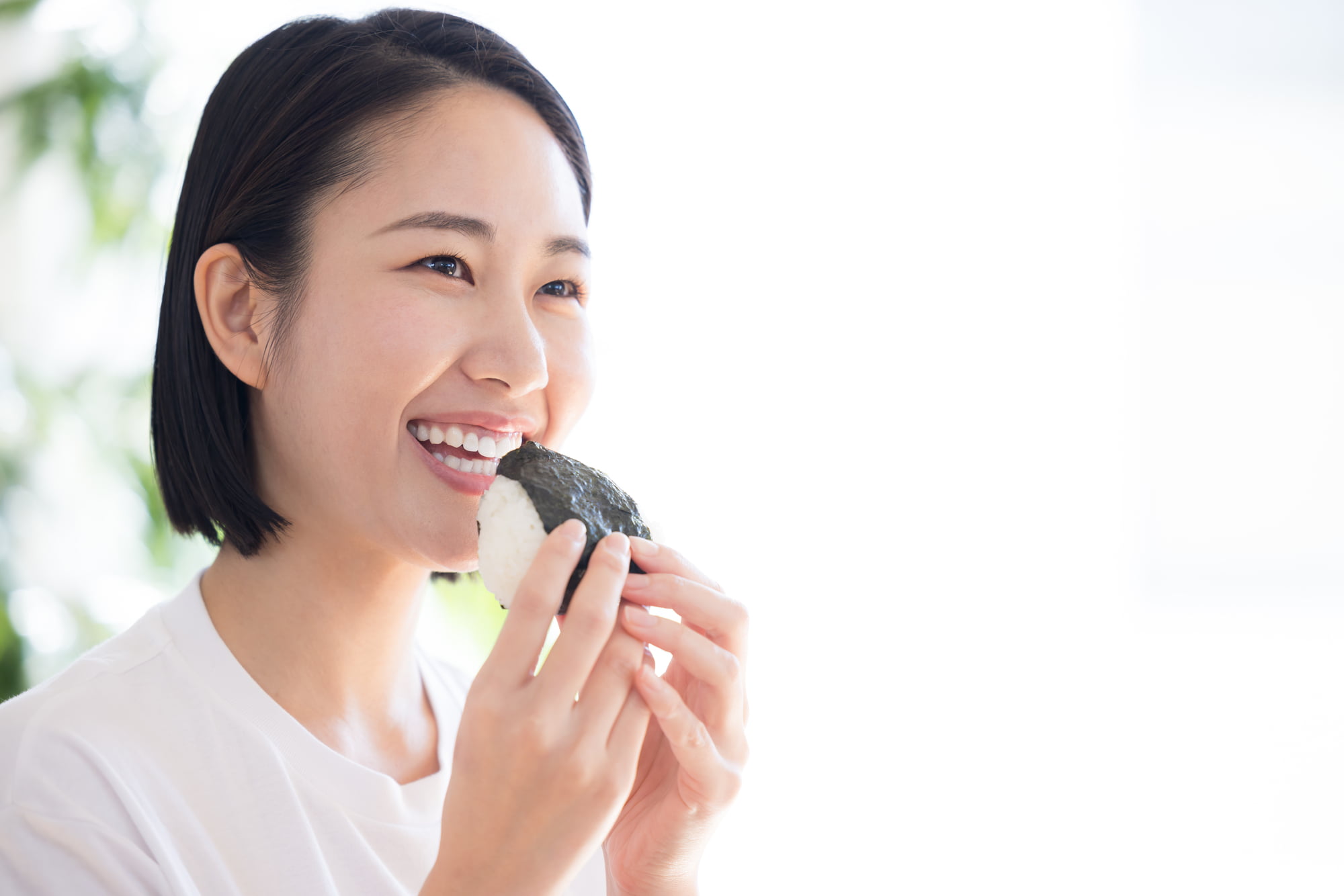 顎関節症を治療した女性が痛みなくおにぎりを食べているイメージ